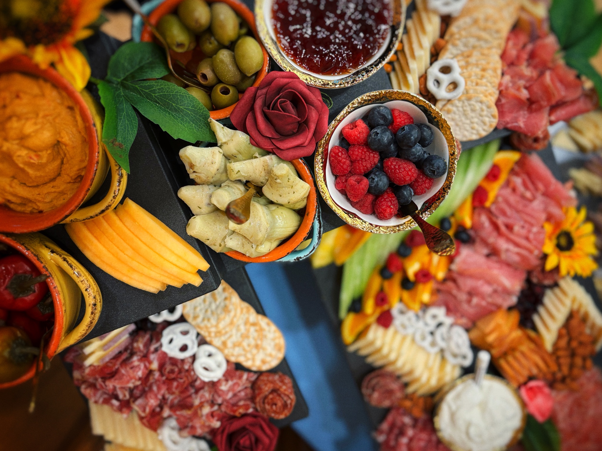 Two Guys Catering grazing display with cheeses, cured meats, berries, olives, artichokes, and crackers