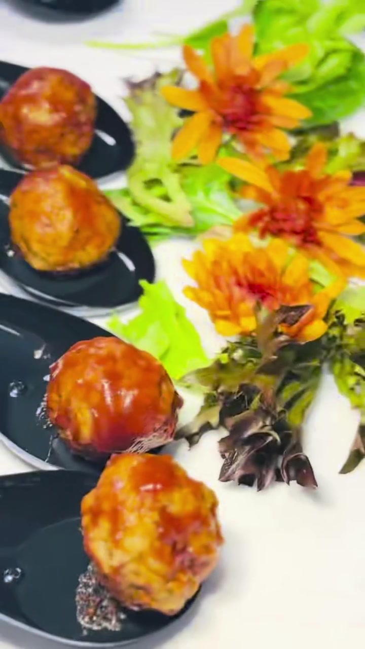 Bourbon mini meatballs presented in black tasting spoons with colorful flowers
