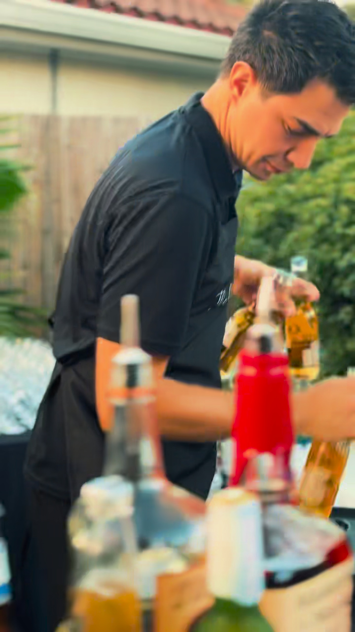 A Two Guys bartender preparing drinks at the courtyard wedding bar